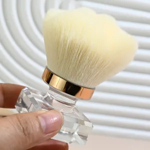 Detail view of a clear crystal handle nail dust brush with soft bristles and gold ferrule.