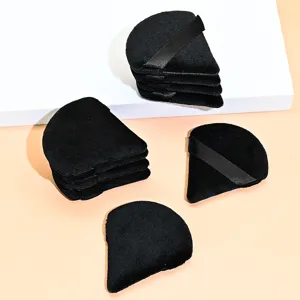 Detailed view of black triangular velvet powder puffs with ribbon straps for makeup.