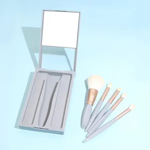 Portable 5-piece makeup brush set with mirror, grey compact case for travel beauty use.