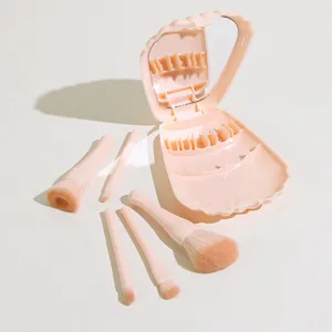 Nahaufnahme eines niedlichen pinken Muschel-Make-up-Pinsel-Sets mit Spiegel und fünf Pinseln.