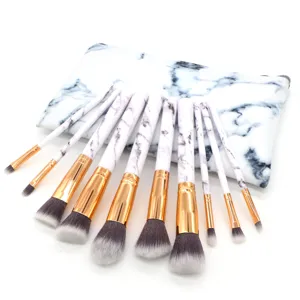 Close up detail view of marble pattern makeup brush set with golden ferrule and pouch.