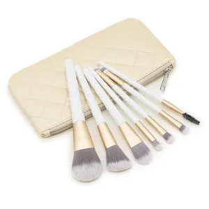 Gedetailleerde close-up van de make-up kwastset met witte gewatteerde handvatten en gouden etui.