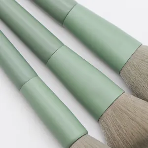 Close up of matcha green makeup brush set bristles and wooden handles, soft cosmetic tools.