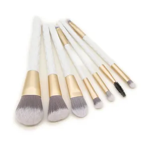 Set van 7 make-up kwasten met witte gewatteerde handvatten en gouden ferrules voor cosmetica.