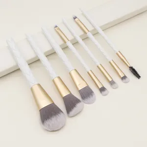 Close-up van een 7-delige make-up borstelset met witte gewatteerde handvatten en gouden hulzen.