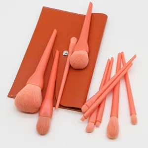 Close-up detail of soft coral makeup brushes set with matching portable storage pouch.