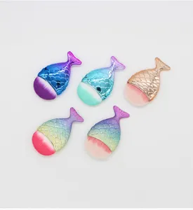 Detail shot of small mermaid tail makeup brush with soft bristles and gradient color handle.