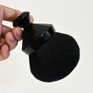 Gros plan du pinceau de maquillage à poignée diamant noire et poils denses et doux.