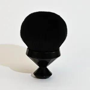 Gros plan sur le pinceau de maquillage noir poils doux manche géométrique pour poudre.