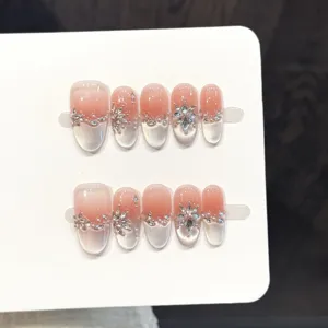 Gros plan faux ongles faits main avec dégradé effet œil de chat et strass brillants.