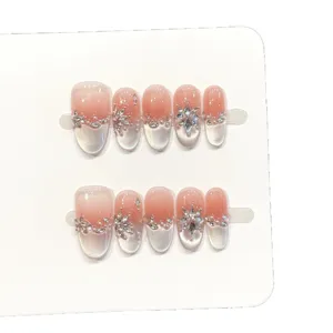 Faux ongles faits main avec effet cat eye transparent, dégradé subtil et strass brillants.