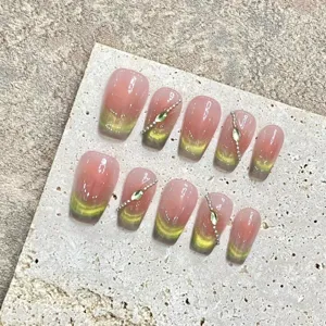 Gros plan de faux ongles effet œil-de-chat dégradé avec strass sur présentoir en pierre.