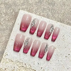 Gros plan détaillé de faux ongles bordeaux effet œil-de-chat avec de superbes strass en feuilles.