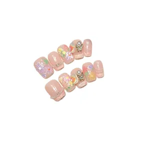 Faux ongles élégants pour le printemps et l'été avec des fleurs peintes et des perles.
