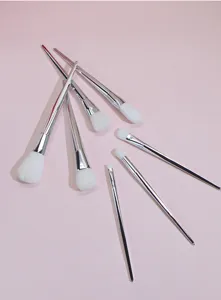7-piece professional makeup brush set with white bristles and silver handles for face and eyes.