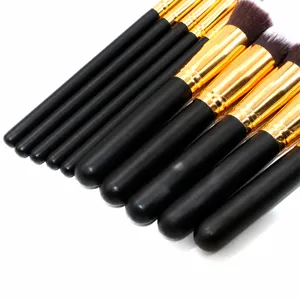 Kit de 10 pinceaux de maquillage avec manches en bois noir et viroles or, vue dessus.