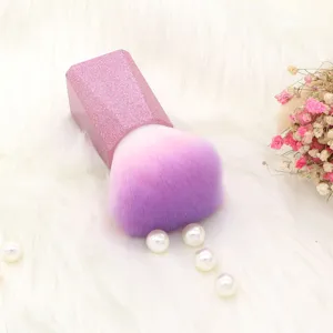 Detail shot of a gradient purple pink powder makeup brush with sparkly handle on white rug.