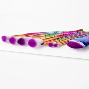 Detailed view of colorful mermaid makeup brushes set with purple bristles and scaly handle.