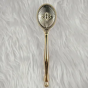 Detailaufnahme des goldenen Vintage-Make-up-Pinsels mit verziertem Griff und Sonnenmotiv.