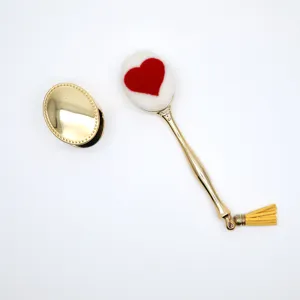 Detailansicht des herzförmigen Make-up-Pinsels mit goldenem Griff und gelber Quaste.