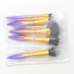 7-teiliges Make-up-Pinsel-Set mit lila-goldenen Griffen und transparentem Aufbewahrungsbeutel.