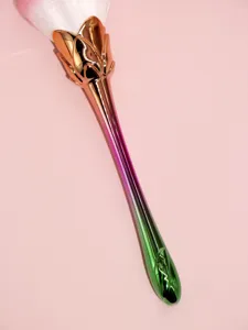 Detail shot of gradient metal rose makeup brush with soft bristles and flower stem handle.