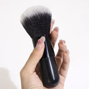 Detail view of the black cosmetic powder brush featuring soft bristles and thick handle.
