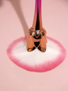 Detailed close-up of gradient rose makeup brush with soft bristles and metallic handle.