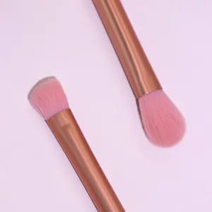 Close-up detail of soft pink makeup brushes with rose gold metallic handles for precise eye makeup.