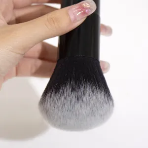 Close-up detail of a soft black and white gradient makeup brush with a thick handle.