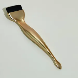 Detail of gold liquid foundation brush with spatula, flat makeup brush for flawless finish.
