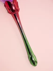 Closeup of a gradient rose makeup brush featuring a metallic handle and soft bristles.