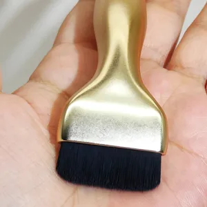 Close-up detail of the flat makeup brush showing soft black bristles and golden handle.