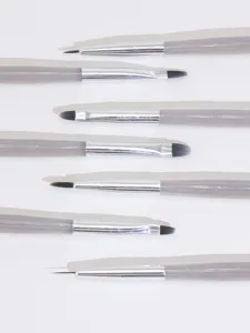 Detailed view of professional acrylic nail art brushes with gray handles and fine bristles.