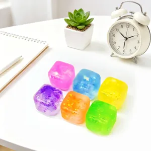 Nahaufnahme von bunten Glitzer-Eiswürfel-Antistressspielzeugen auf weißem Tisch.