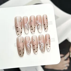 Dettagli unghie finte fatte a mano con sfumatura cat eye e decorazioni floreali 3D.