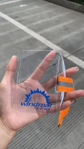 Detailaufnahme des transparenten Armband-Ausweishalters mit orangem elastischem Gurt.
