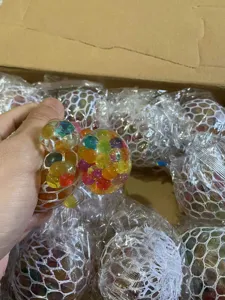 Close-up of colorful mesh stress ball hand squeezed, sensory decompression toy detail shot.