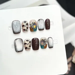 Dettaglio di unghie press-on fatte a mano con glitter cat-eye e nail art leopardata.