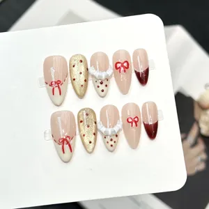 Unghie finte fatte a mano con fiocchi rossi e glitter dorati per un look elegante e quotidiano.