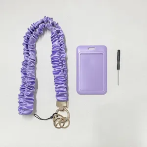 Detailansicht des lila Satin Scrunchie Umhängebandes, Ausweishalter und Schlüsselanhängers.