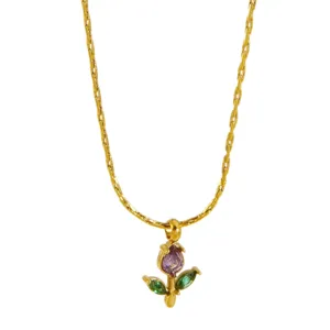 Gold flower pendant necklace close up, delicate purple and green stone floral detail.