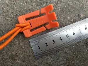 Outdoor multi-functional orange tent rope buckle with elastic cord gear fastening tool.
