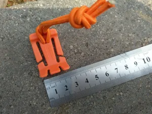 Outdoor tactical rope buckle detail, orange plastic camping gear tensioner and elastic cord accessory.