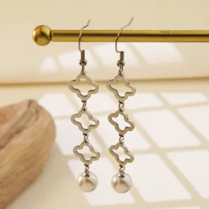 Primer plano detallado de pendientes de acero inoxidable con trébol y perlas colgantes.