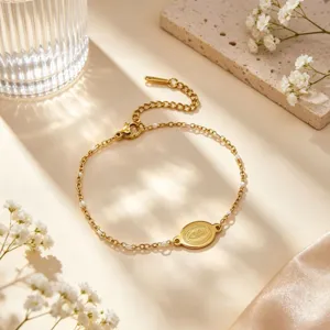 Gold plated stainless steel bracelet detail, elegant oval pendant and white enamel bead links.
