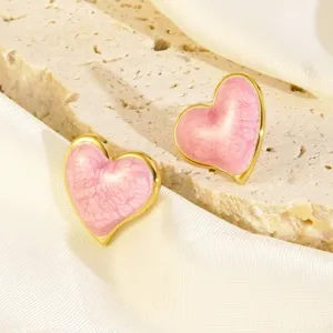 Detailopname van trendy roze geëmailleerde hartvormige oorbellen met gouden rand.