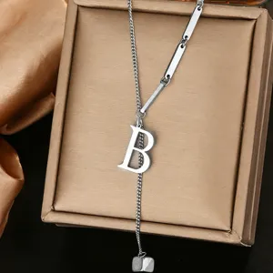 Closeup of stylish stainless steel letter B pendant necklace with geometric links on box.