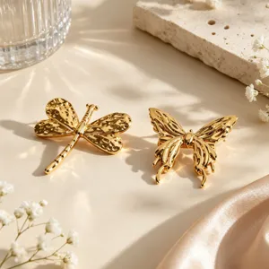 Close-up detail shot of gold-plated dragonfly and butterfly metal brooches on aesthetic props.