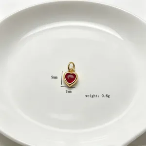 Nahaufnahme eines kleinen roten Zirkon-Herzanhängers mit vergoldetem Finish, Detail 9x7mm.